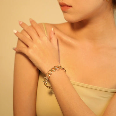 Cropped wrist-level shot of a woman in a crop top, wearing the stylish heart cuff bracelet from the Jewels of St Leon Urban Jewellery Bracelet Collection.