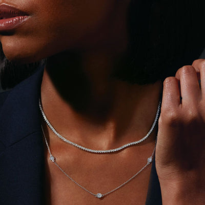 Female model adorned in Jewels of St Leon's Dazzling Diamonds Collection, featuring a lab-grown diamond tennis necklace and natural diamond station necklace, both in 14kt white gold. Shop now for responsibly sourced luxury!