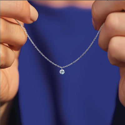 Lab-Grown Diamond Necklace Collection: Model holds a 14kt white gold chain with a solitaire lab-grown diamond brilliant round pendant.
