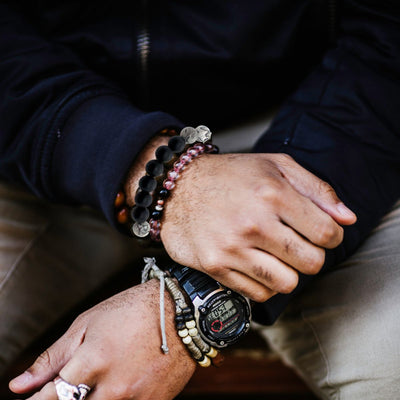A man confidently wears a stack of men's bracelets, showcasing a mix of leather and stainless steel designs. The bracelets add a bold and sophisticated touch to his outfit, perfect for modern men's fashion.