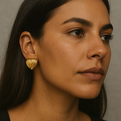 Close-cropped image of a brunette model, tilting her head to reveal chunky 18 K gold-plated Heart Shell Studs from the Urban Earrings collection.