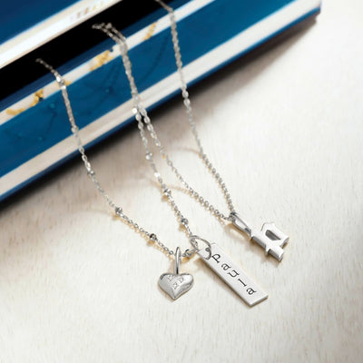 Women's white gold necklace collection: Heart pendant with three natural diamond accents & flat bar pendant engraved 'Paula' on satellite chain, separate cable chain with initial 'P' pendant.