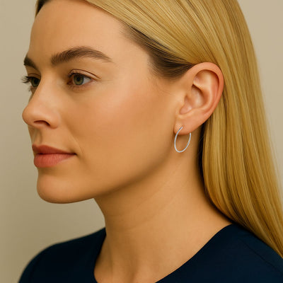 Close-up of a woman wearing 1.5mm x 20mm Sterling Silver hinged endless hoop earrings. Slim tube design hugs the earlobe, with polished finish and secure fit.