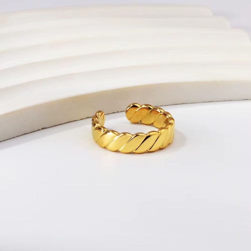A polished 18K gold-plated stainless steel flattern twisted ring with a sleek, modern design.