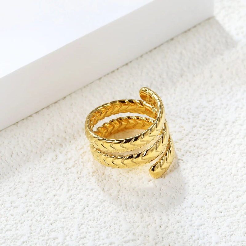 A stunning 18K gold-plated stainless steel wrap-around snake ring with an intricate scale design, coiled on a soft background. The polished gold finish enhances its bold and elegant appeal.