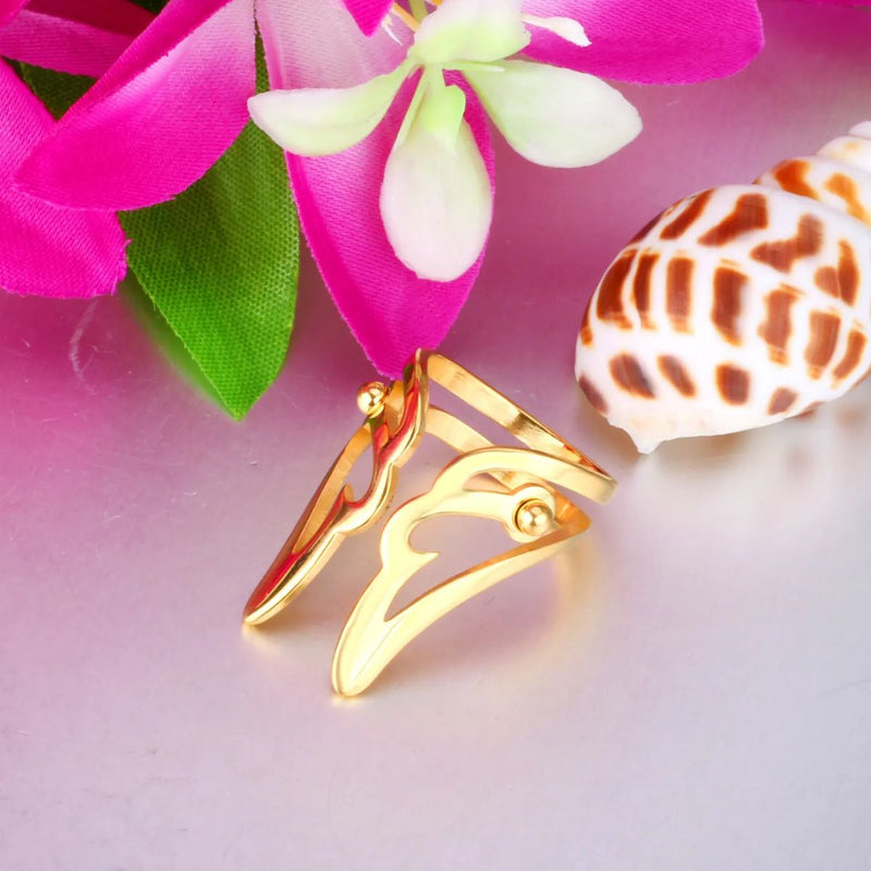 Fashion wing-shaped ring in 18K gold-plated stainless steel. A stunning, detailed wing design in a lightweight, durable gold ring for women’s jewellery surrounded by vivid colour, flowers and a seashell, enhancing the rings beauty.