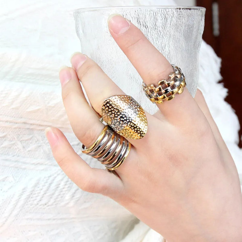 A range of stunning tri-tone rings featuring yellow gold, rose gold, and silver hues. Each piece is a unique 18K gold-plated statement ring with bold styling.