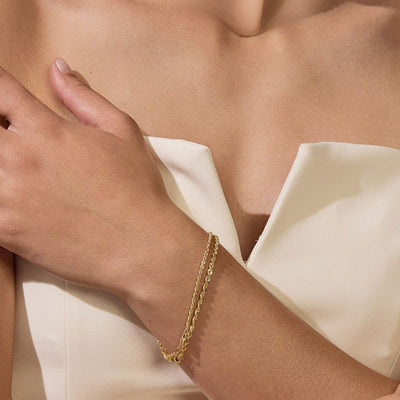 Model wearing 9ct yellow gold rope chain bracelet, layered with other gold chains for an elegant look – Jewels of St Leon.