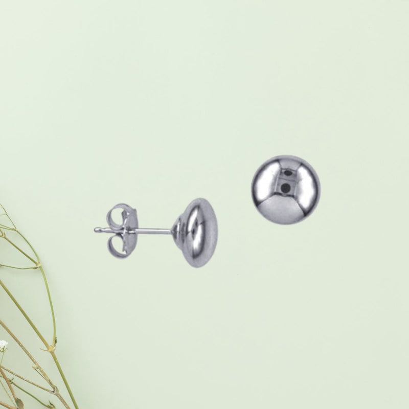 A front and side view on a soft green background with the 6mm Flat Ball Stud Earrings in Sterling Silver highlights their polished finish and minimalistic, unisex design.