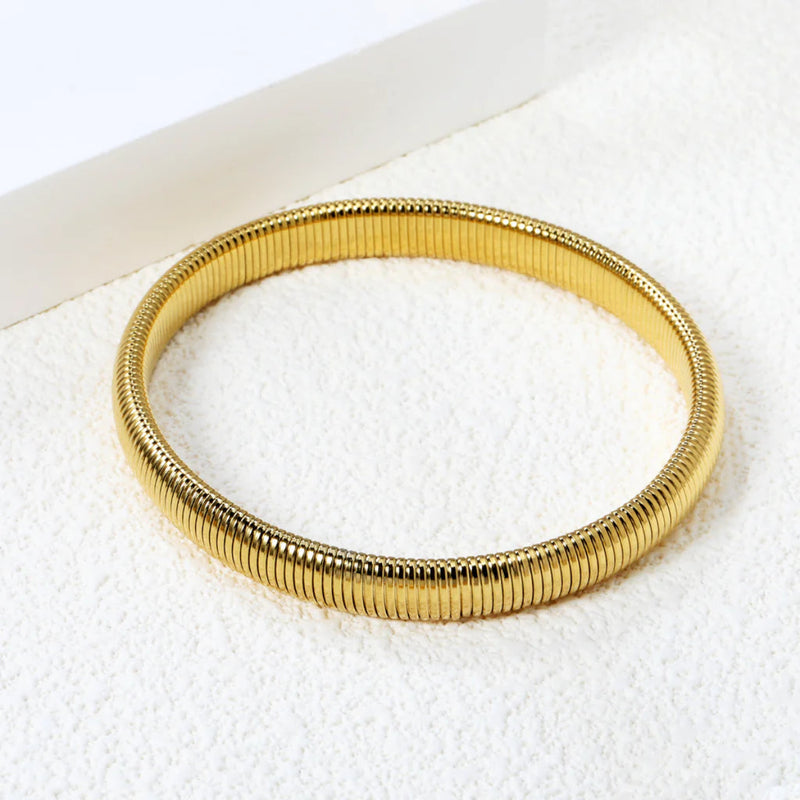 Close-up of the bangles’s fluid design, showcasing its seamless links and high-shine gold finish.