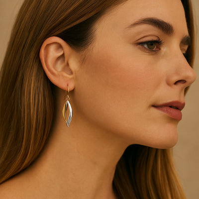 A close-up portrait of a woman wearing 9ct two-tone gold fancy drop earrings, featuring twisted yellow and white gold.