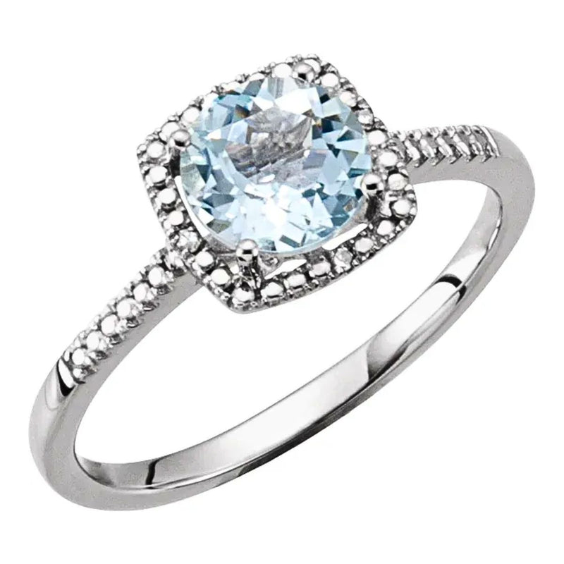 A top view of our Aquamarine and Diamond Halo-Style Birthstone Ring, showcasing the 7mm fine blue natural aquamarine surrounded by a beaded halo of four sparkling diamonds set in rhodium-plated sterling silver. Available from Jewels of St Leon