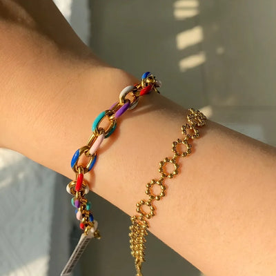  A detailed shot of the bracelet’s enamel finish and polished 18K gold-plated stainless steel chain, highlighting its stylish, adjustable fit.