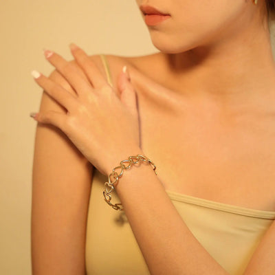 A model wearing the sleek gold cuff bracelet featuring an elegant open heart design, polished in 18K gold plated Stainless Steel for a timeless appeal, that is durable, hypoallergenic, waterproof and tarnish resistant.