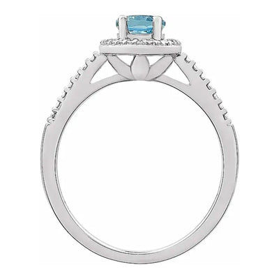 A side view of the Sky Blue 7x5mm Oval Topaz Beaded Halo Ring, emphasising the raised setting of the 7x5mm topaz and the intricate beaded halo design with diamond accents, all crafted in tarnish-resistant rhodium-plated sterling silver. Shop Women's Jewellery from Jewels of St Leon.