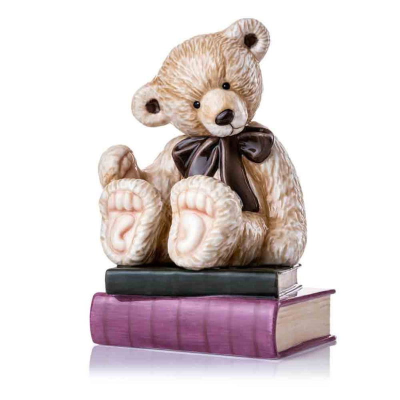 A captivating front view of the 2009 Charlie Bear of the Year figurine, showcasing its soft golden-brown textured fur, glossy oversized bow, and charmingly warm wave.