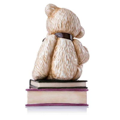 An angled rear perspective captures the graceful curve of the figurine's form, the elegant bow's design, and the fine detailing of the ceramic books underneath.