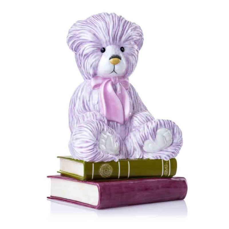  beautiful angled view of the 2024 Charlie Year Bear, highlighting the textural details of its fine bone china fur and the elegant sculpting of the oversized bow and layered books.