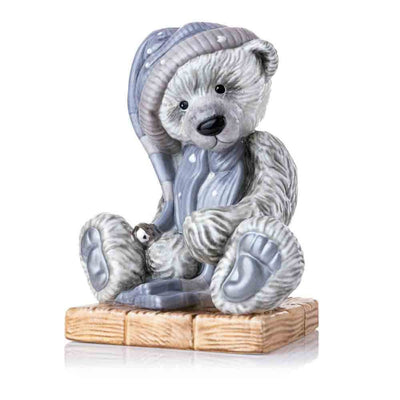 A charming view of Frost, the beloved Charlie Bear, crafted in fine bone china. Frost's soft blue-grey "fur" and platinum-finished bell glisten, showcasing the intricate hand-painted details and signature winter hat and scarf.