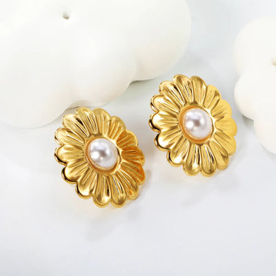 Lifestyle photo of the gold daisy pearl earrings styled amid soft white décor shapes, highlighting their luminous petals.