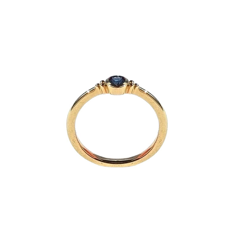 A side view of the ELLIN Ring, capturing the profile of the 3.75mm blue sapphire and the fine craftsmanship of the 9kt yellow gold band, showcasing its smooth finish and sophisticated style. Shop gold rings from Jewels of St Leon.
