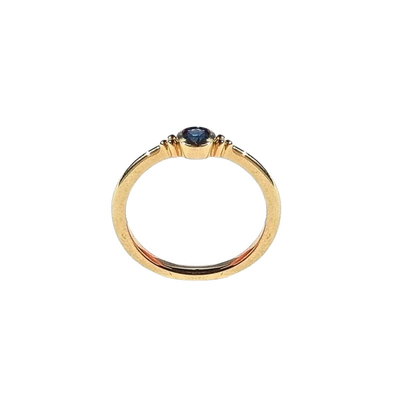 A side view of the ELLIN Ring, capturing the profile of the 3.75mm blue sapphire and the fine craftsmanship of the 9kt yellow gold band, showcasing its smooth finish and sophisticated style. Shop gold rings from Jewels of St Leon.
