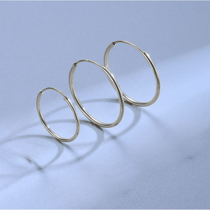 Sterling silver endless hoop earrings trio in 40mm, 50mm and 60mm on light blue background