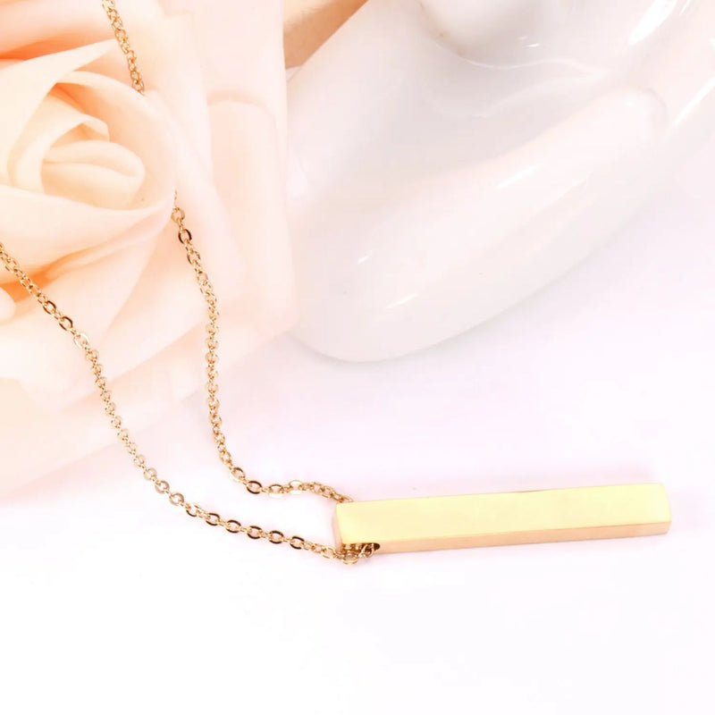 The 18K gold-plated bar pendant necklace displayed alongside a soft pink rose, creating a romantic and stylish presentation.