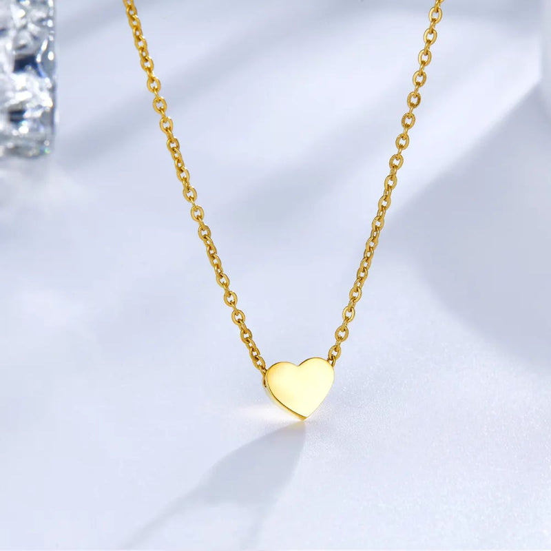 The gold heart necklace elegantly displayed on a soft background, showcasing its sleek 45cm chain, engraved charm, and polished finish.