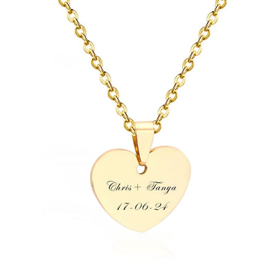 A romantic close-up of the Engravable Heart Necklace in 18K Gold-Plated Stainless Steel, beautifully inscribed with a couples name - an unforgettable symbol of love in Edwardian Script.