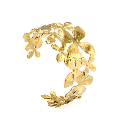 A floral-inspired gold cuff bangle, featuring a wrap-around open design with detailed flower motifs. This cuff bracelet is Hypoallergenic, waterproof and tarnish resistant.