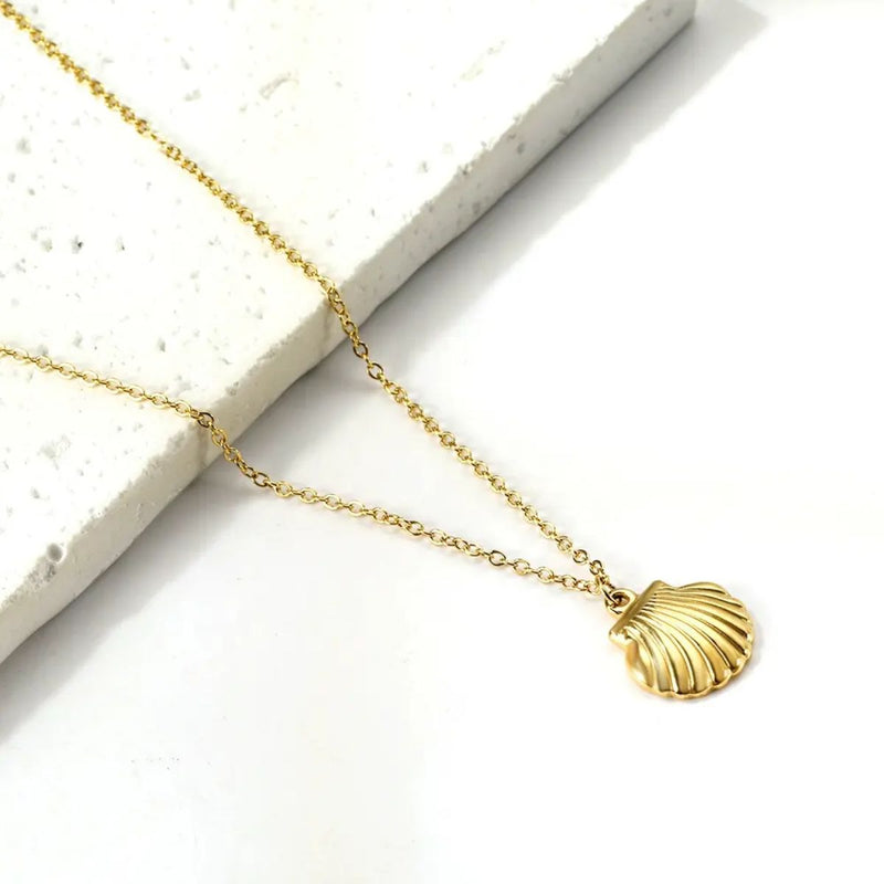 Close-up of the 18K Gold Plated Shell Necklace resting gently against marble, showcasing its gleaming finish and delicate coastal-inspired pendant.