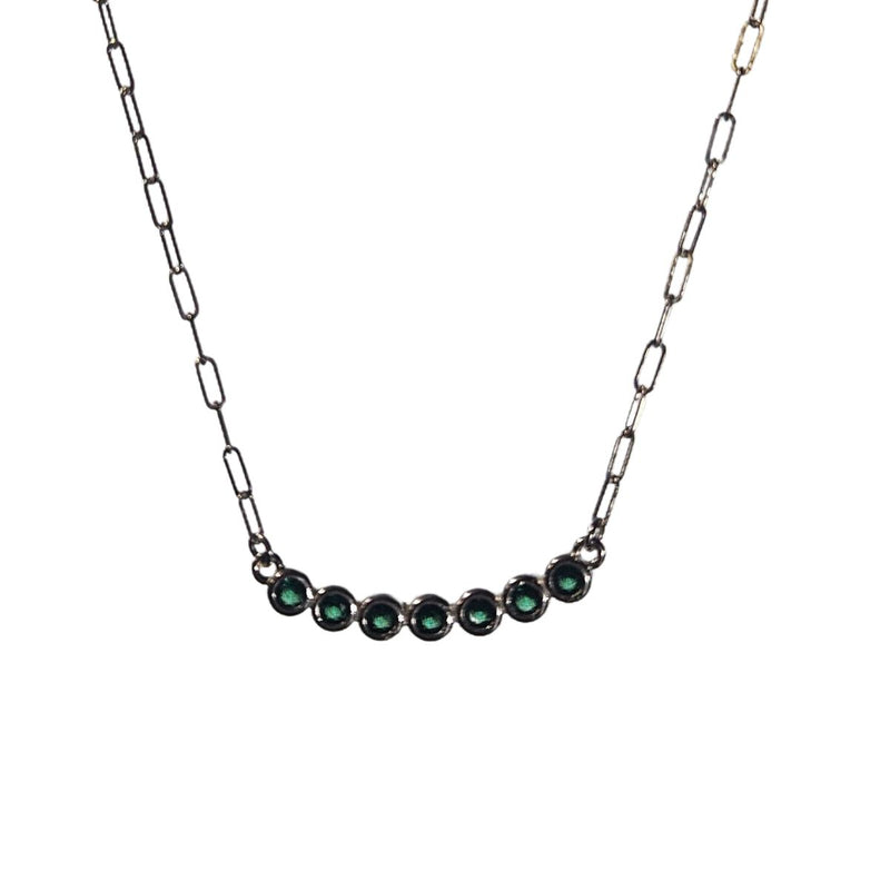 A close-up of the Green CZ Curved Bar Necklace, featuring a sterling silver 32.5x4.3mm curved bar adorned with seven vibrant green CZ stones, elegantly set on a 49cm, 2mm paperclip chain for a modern, sophisticated look.