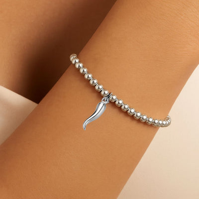 Sterling silver 4 mm beaded bracelet featuring a 13 × 4 mm Cornicello Italian horn charm, elastic design with anti-tarnish finish worn by a model.