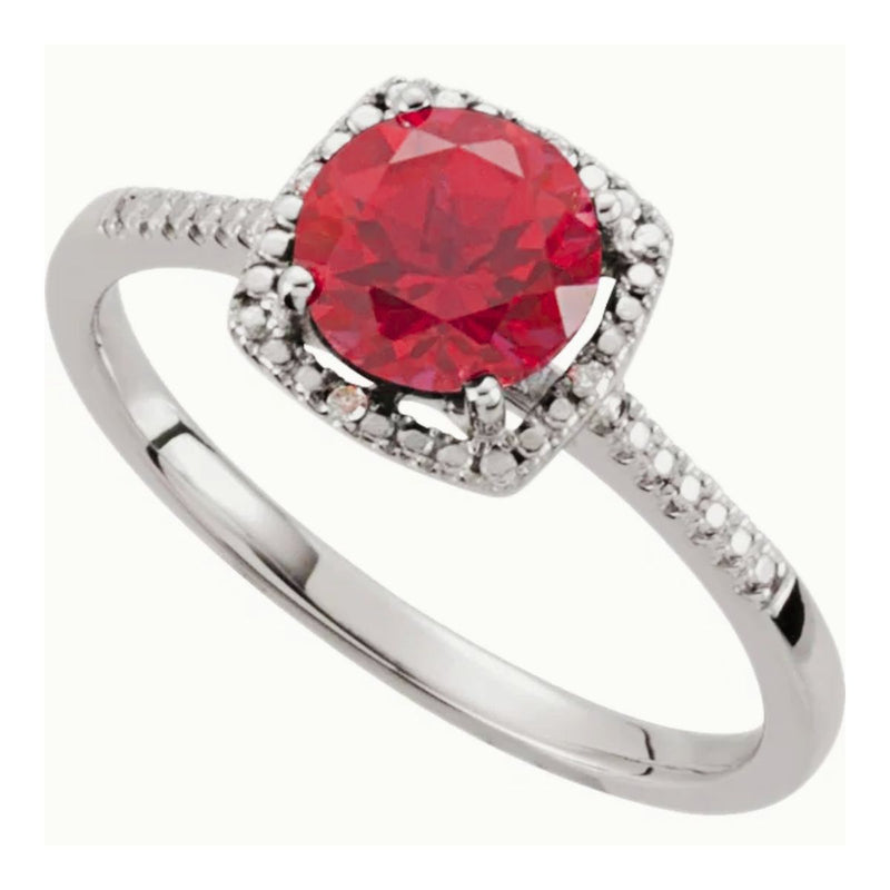 Top 45 degree view of a 7mm lab-created ruby set in a halo-style design with 0.01ctw diamonds and beaded edging. This ladies sterling silver ring is a blend of luxury and affordability. Shop now at Jewels of St Leon