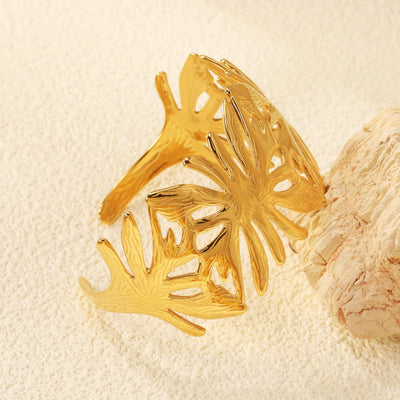Close-up of the textured leaf pattern resting against a stone. This waterproof and anti-tarnish cuff showcases the intricate details and its adjustable fit.