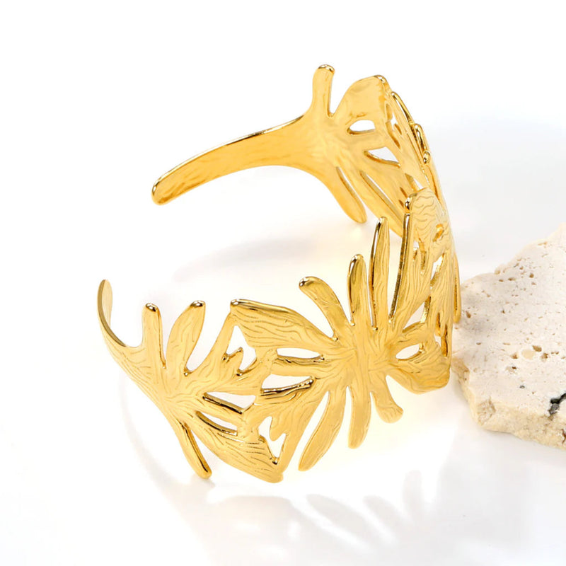 A statement leaf-inspired cuff bangle with an open wrap-around design, polished in 18K gold-plated stainless steel for a luxurious finish.