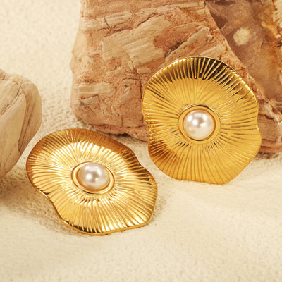 Textured gold-plated lotus-shaped stud earrings with white pearl centres displayed against rugged sandstone, highlighting their rippled petals.