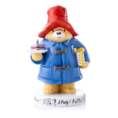 Paddington Bear: A Party Colour Figurine - Paddington is featured with his Blue Duffle, iconic red hat and with a piece of cake with a candle and a present under his arm. Set on a beautiful base with iconic London Motifs.