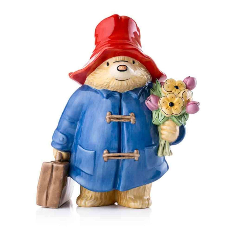 The Paddington Large Figurine is shown standing tall at 25cm, with vibrant hand-painted details, featuring his signature blue coat, red hat, and a charming bouquet of flowers.