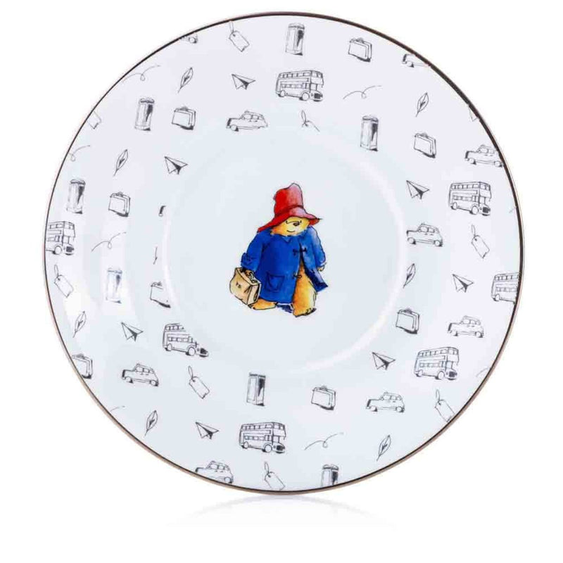 A detailed view of the Paddington design, showcasing the vivid red and blue colours of his attire, framed by delicate platinum accents and sketch-style London icons.