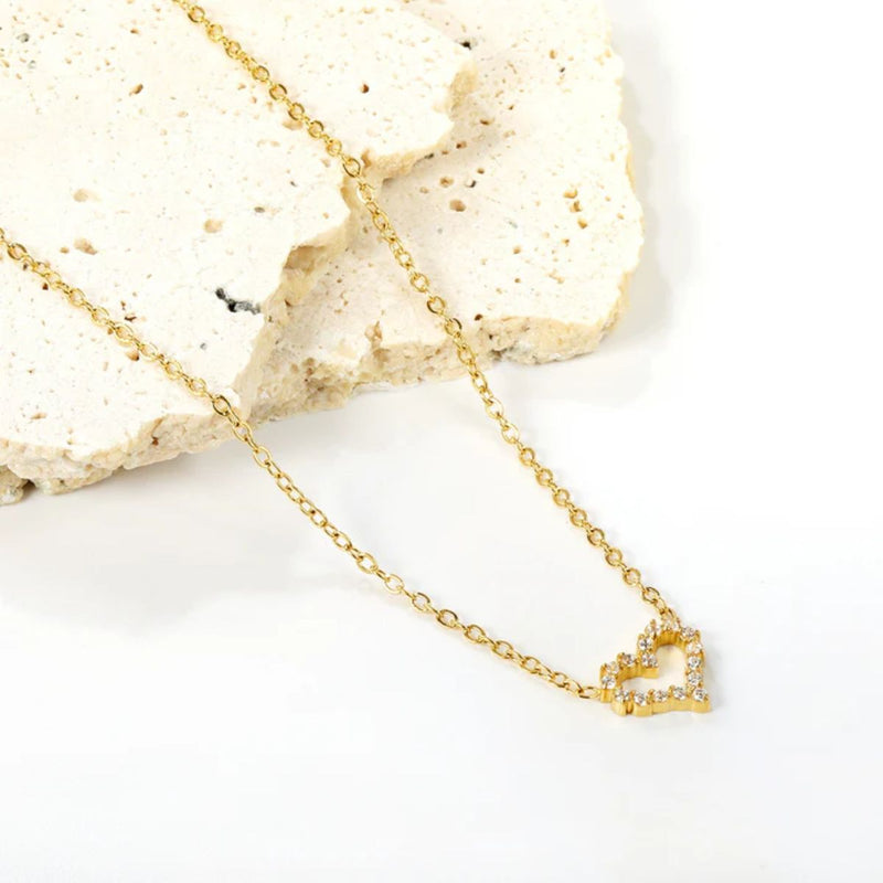 Heart necklace gently draped across smooth white sandstone pieces, creating a soft, romantic setting that highlights its delicate charm.