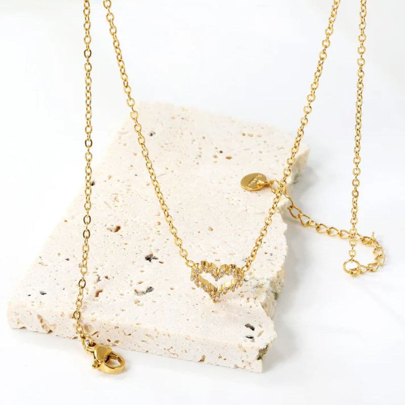 Top-down view of the necklace on a white sandstone background, showing the full chain and pendant in natural light for a warm, feminine feel.