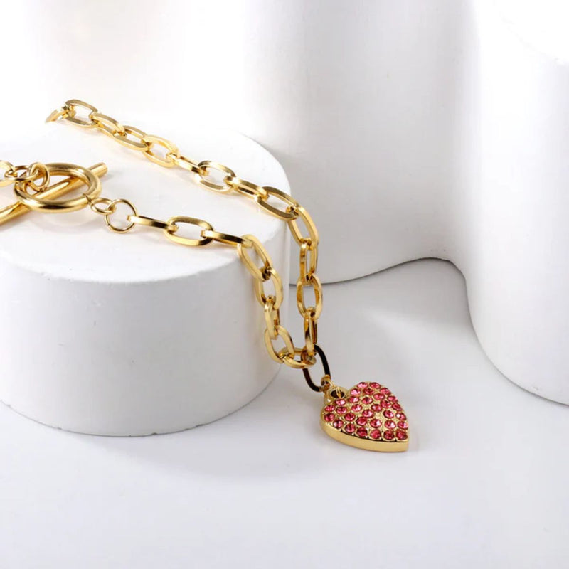 Heart pendant draped gracefully down a round display, with the paperclip chain flowing naturally to showcase movement and modern style.