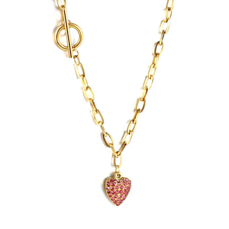 Close-up of the 12.8x16.4mm heart pendant with pink CZ accents, the toggle clasp and bold paperclip chain, highlighting texture and golden detail.