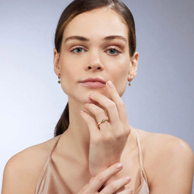 A front-on view of the Quinn Ring on a model's hand, showcasing the stunning green sapphire and the square setting. The 9kt yellow gold band adds a touch of elegance to the overall look. Shop rings for women at Jewels of St Leon.