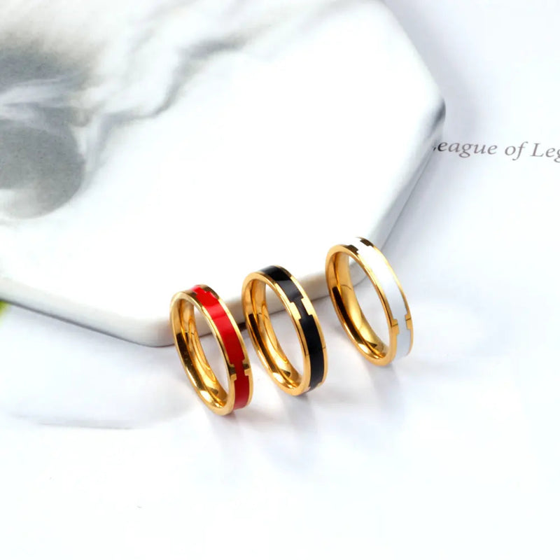 A striking trio of 18K gold-plated stainless steel stackable bands with vibrant red, black and white enamel detailing. A modern and stylish unisex ring.