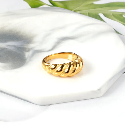 Sitting on a marble coaster is the trendy 18K gold-plated stainless steel croissant ring with a curved design. A statement ring inspired by modern fashion.