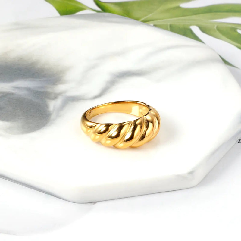 Sitting on a marble coaster is the trendy 18K gold-plated stainless steel croissant ring with a curved design. A statement ring inspired by modern fashion.