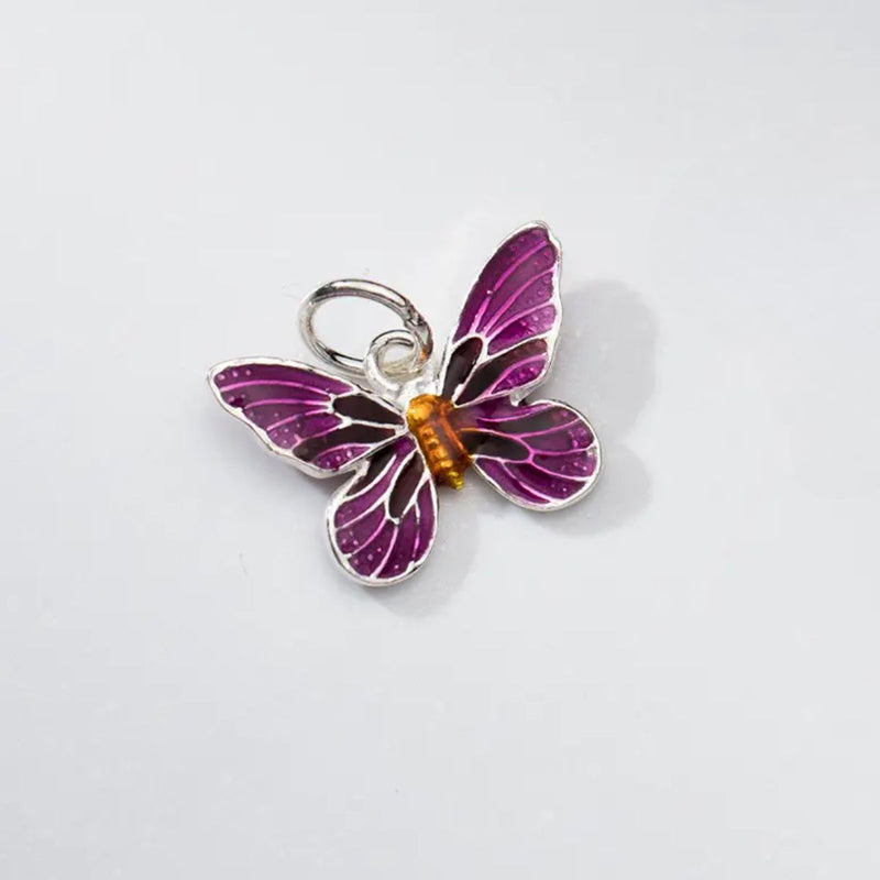 A close-up of the Purple Enamel Butterfly Charm Pendant, highlighting its exquisite sterling silver design with intricate purple and gold enamel detailing.